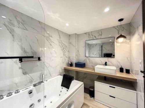 une salle de bain avec une baignoire, un lavabo et un miroir dans l'établissement BRP Cannes Center,Two-Bed Deluxe Apart with Spa bath, à Cannes