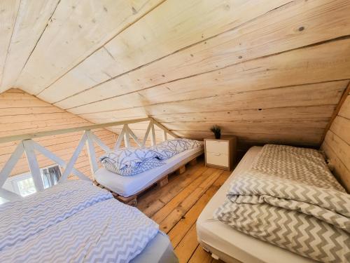 two beds in a room with a wooden ceiling at Osada Kryspinów in Cholerzyn