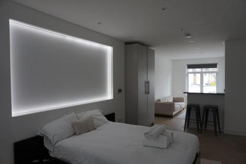 a bedroom with a white bed and a large window at Luxurious London Studios in Harrow