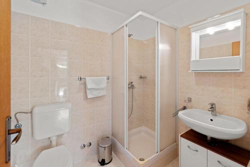 een badkamer met een douche, een toilet en een wastafel bij Garden Rooms Chiara in Poreč