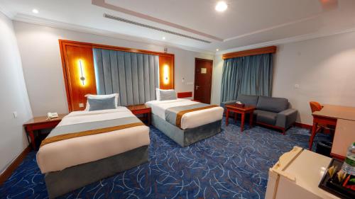 a hotel room with two beds and a couch at Al Masem Serviced Apartments - Gharnata - Exit 9 in Riyadh