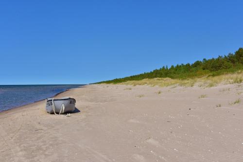 a suitcase sitting on a beach next to the water at Jaunklāvi in Sīkrags