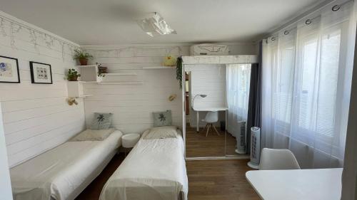 een kleine kamer met 2 bedden en een bureau bij Le Bayanas in La Rochelle