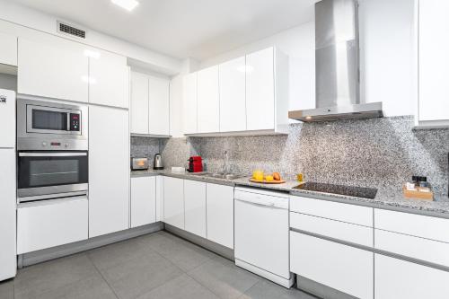 a white kitchen with white cabinets and appliances at The Corner Apartments by Aspasios in Barcelona