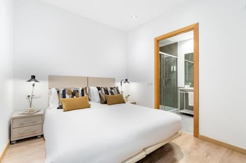 a bedroom with a large white bed and a mirror at The Corner Apartments by Aspasios in Barcelona