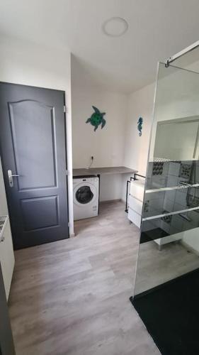 une salle de bains avec une porte et un lave-linge. dans l'établissement Le Frêne Chantant, à Bazinval