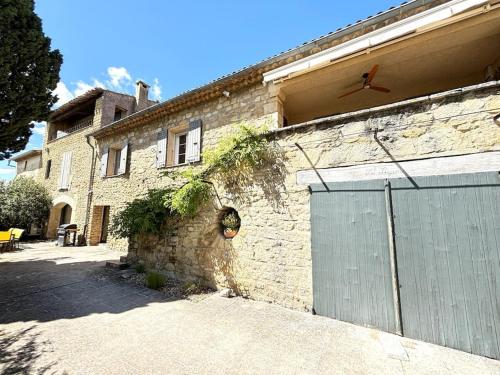 un bâtiment en briques avec un portail et un garage dans l'établissement Superbe Mas en Pierre, Piscine, Boulodrome, 14 pers, à Sarrians