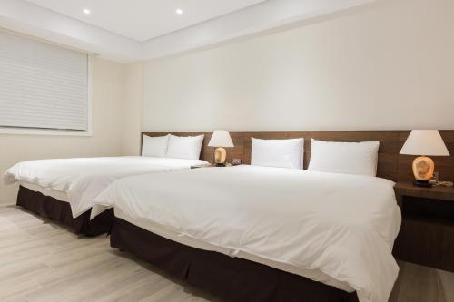 two beds in a hotel room with two lamps at Lanven Art House in Hualien City