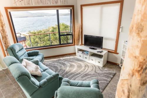 een woonkamer met 2 stoelen en een televisie bij Larus Waterfront Cottage in White Beach