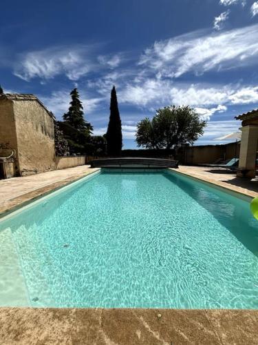 une grande piscine d'eau bleue dans une cour dans l'établissement Superbe Mas en Pierre, Piscine, Boulodrome, 14 pers, à Sarrians
