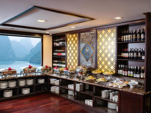 a restaurant with a counter with food and wine bottles at Amanda Luxury Cruise in Ha Long