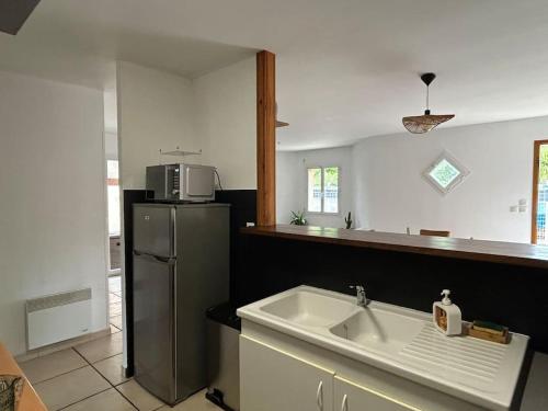 une cuisine avec un évier et un réfrigérateur dans l'établissement Maison cosy proche du lac, à Lacanau