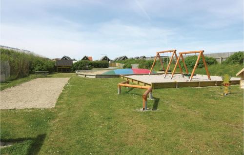 a playground with a swing set in the grass at Hytte 23 in Thyborøn