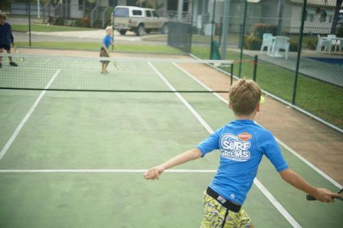 two young children playing tennis on a tennis court at BIG4 Tasman Holiday Parks - Rowes Bay in Townsville