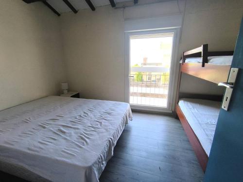 une chambre avec un lit et une fenêtre avec un balcon dans l'établissement 190 CAP D'AGDE, Villa mitoyenne avec jardinet et parking, au Cap d'Agde