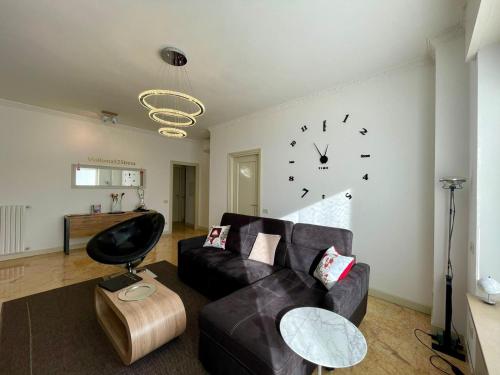 ein Wohnzimmer mit einer Couch und einer Uhr an der Wand in der Unterkunft Family Apartment Vista Lago in Stresa