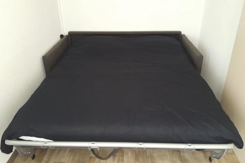 Cama en habitación con colchón negro en Studio city center, en Les Rousses