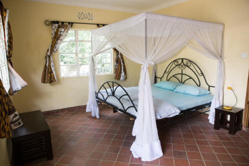 a bedroom with a bed with a canopy at Coffee Farm Guest House in Nkoaranga