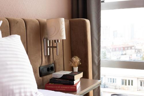 a bed with a lamp on a table with books at Hotel Sirius in Pristina