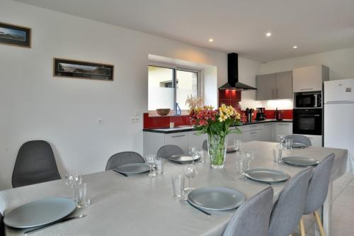une table à manger avec des chaises et un vase de fleurs dans l'établissement Maison récente Le Cellier à Dol-de-Bretagne proche Mont-Saint-Michel, à Dol-de-Bretagne