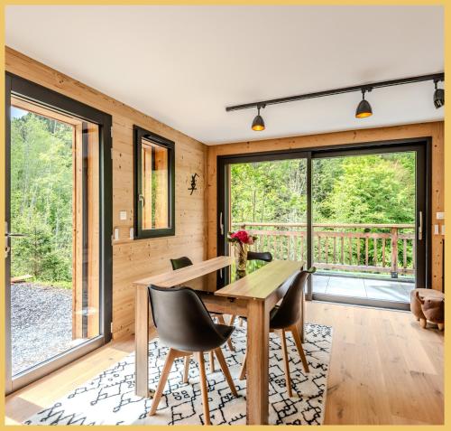 une salle à manger avec une table, des chaises et des fenêtres dans l'établissement Le Solaris I Morzine, à Morzine