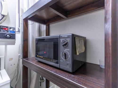 a microwave oven sitting on a wooden shelf at Tabist City Hotel Patio in Takamatsu