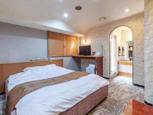 a bedroom with a large bed and a kitchen at Tabist City Hotel Patio in Takamatsu