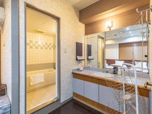 a bathroom with a sink and a tub at Tabist City Hotel Patio in Takamatsu