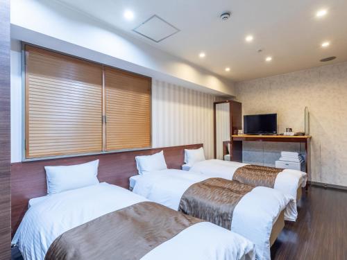 a hotel room with four beds and a tv at Tabist City Hotel Patio in Takamatsu