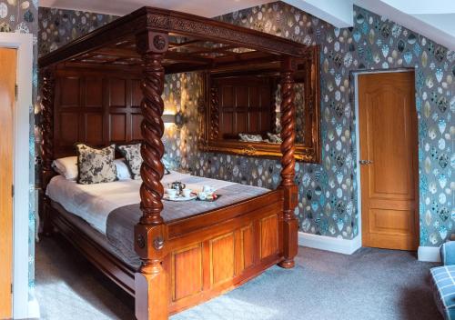 a bedroom with a wooden canopy bed in a room at Broadoaks Boutique Country House in Windermere