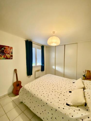 - une chambre avec un lit et une guitare dans l'établissement Appartement 6 personnes, à La Londe-les-Maures