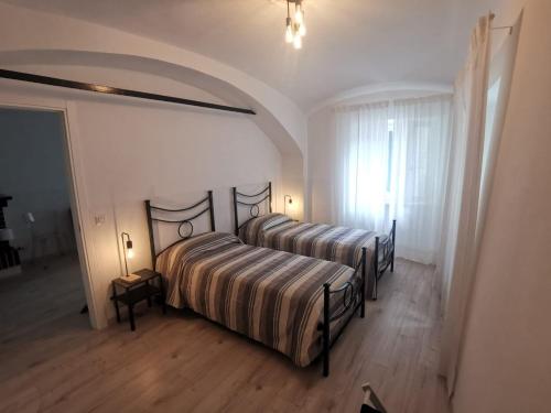 a bedroom with two beds in a room with wooden floors at Casa del barbiere in Dogliani