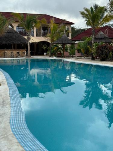 a swimming pool with blue water in front of a resort at Paje Blu Boutique Hotel in Paje