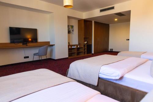 a hotel room with three beds and a flat screen tv at Hotel Sirius in Pristina