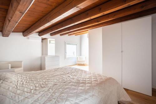 パレルモにあるPalazzo del Buonpastore by Casa Azzurra Apartmentsの白いベッドルーム(ベッド1台付)と木製の天井が備わります。