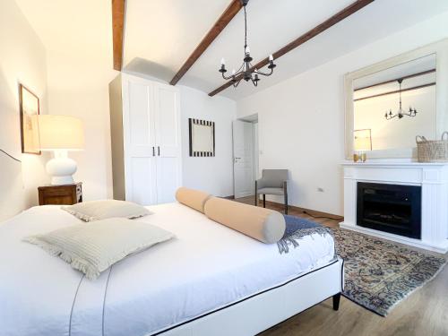 a white bedroom with a bed and a fireplace at ComeCasa Langhe Garden House-Pace e Panorama a Benevello in Benevello
