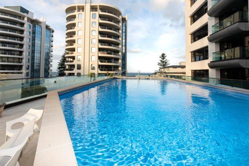 a large swimming pool in the middle of two buildings at Seaside at Eleven Mt Maunganui in Mount Maunganui