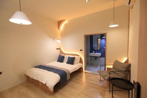 a bedroom with a bed and a chair and a sink at Green Inn Kaohsiung in Kaohsiung