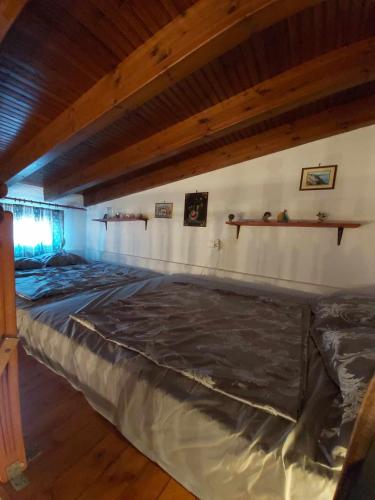a large bed in a room with a wooden ceiling at Villa Velika GR in Velika