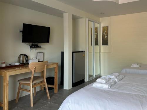 a hotel room with a bed and a desk and a television at Mangoes Pattaya in Na Jomtien