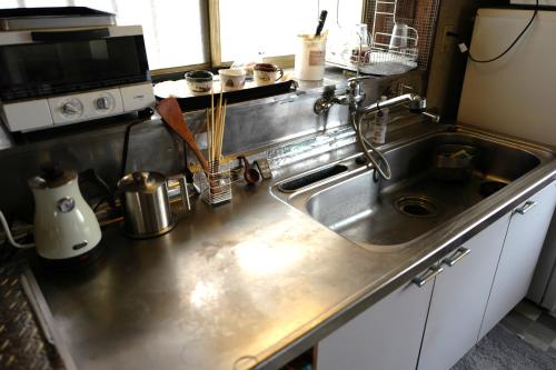 a kitchen with a stainless steel sink and a microwave at 海と西一棟貸し宿 in Saitsuno