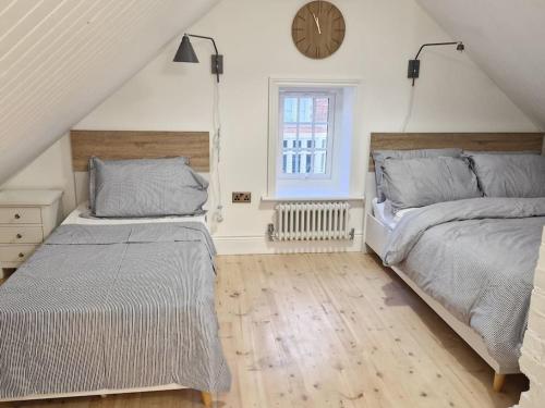 a bedroom with two beds and a clock on the wall at Victorian Villa, Hunstanton Norfolk Sleeps 20 in Hunstanton