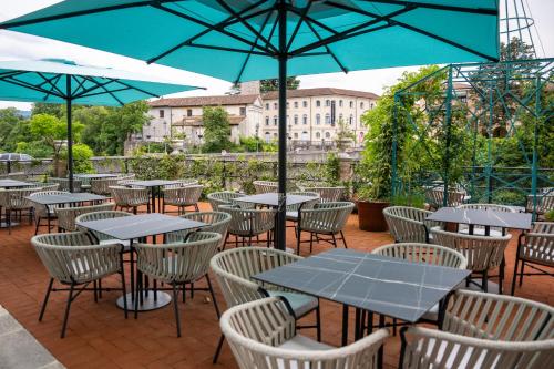 an outdoor patio with tables and chairs and umbrellas at 1448 Antica Dimora Al Merlo Bianco in Cividale del Friuli