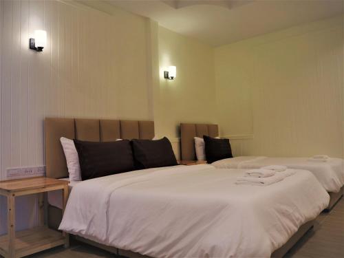 a bedroom with two beds with white sheets at Mangoes Pattaya in Na Jomtien