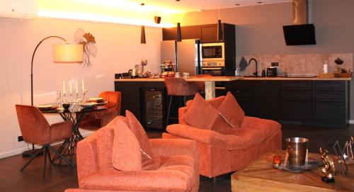 Il comprend un salon avec des chaises orange et une cuisine. dans l'établissement L'ApothéOse, gîte bien-être avec jacuzzi, sauna, hammam, à Lieuron