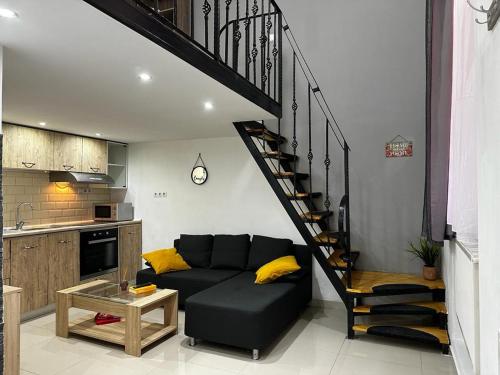 ein Wohnzimmer mit einem schwarzen Sofa und einer Wendeltreppe in der Unterkunft Apartament Studio Ultracentral Oradea in Oradea