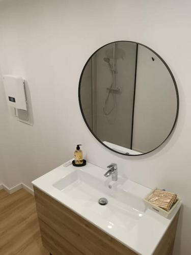 La salle de bains est pourvue d'un lavabo et d'un miroir rond. dans l'établissement Fleur de Lin, à Esquelbecq