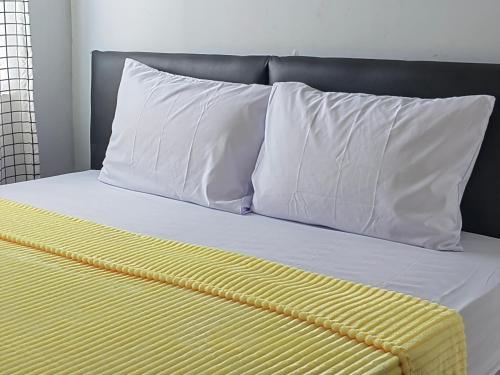 a bed with white pillows and a yellow blanket at Cibubur Village By Arsakha Property Management in Cibubur