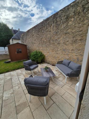d'une terrasse avec 3 chaises, une table et un mur en briques. dans l'établissement Maison cosy au centre historique de Bayeux, à Bayeux