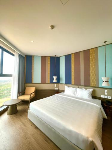 a bedroom with a large white bed and a chair at Apec Mandala Chambay Mũi Né in Ấp Thiẹn Ái